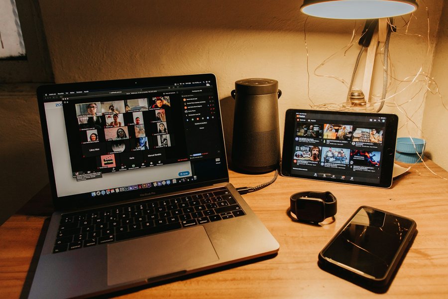 オンライン会議の画面とタブレット、スマートフォンが置かれた机
